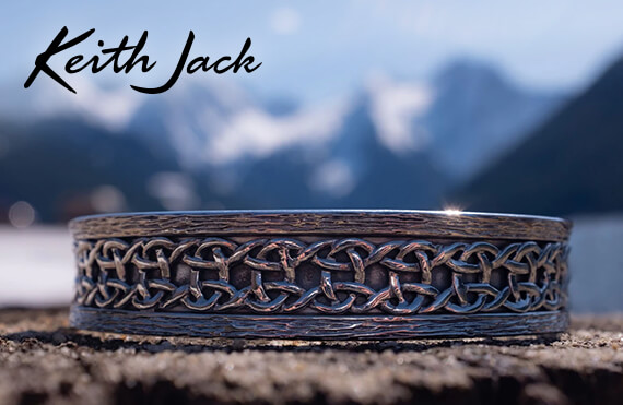 Keith Jack  Jewelry - image of a Keith Jack wedding band with celtic knotwork in front of a blurred mountain scape